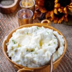 mashed potatoes in a dish topped with butter and a pinch of chopped parsley