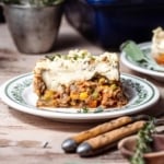 Square serving of shepherds pie on a plate, two forks in the foreground.